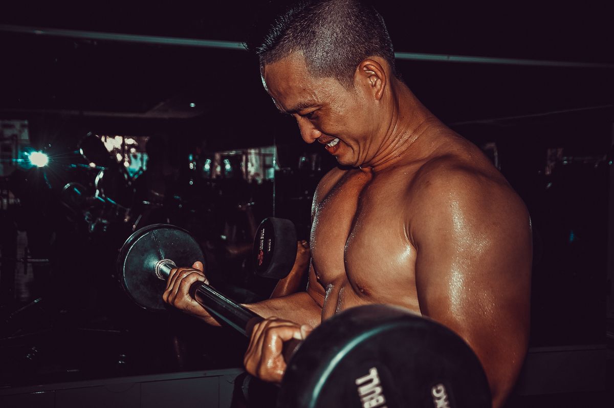 How to build muscle: a beginner training and food plan | the gym pro Man Performing A Barbell Curl