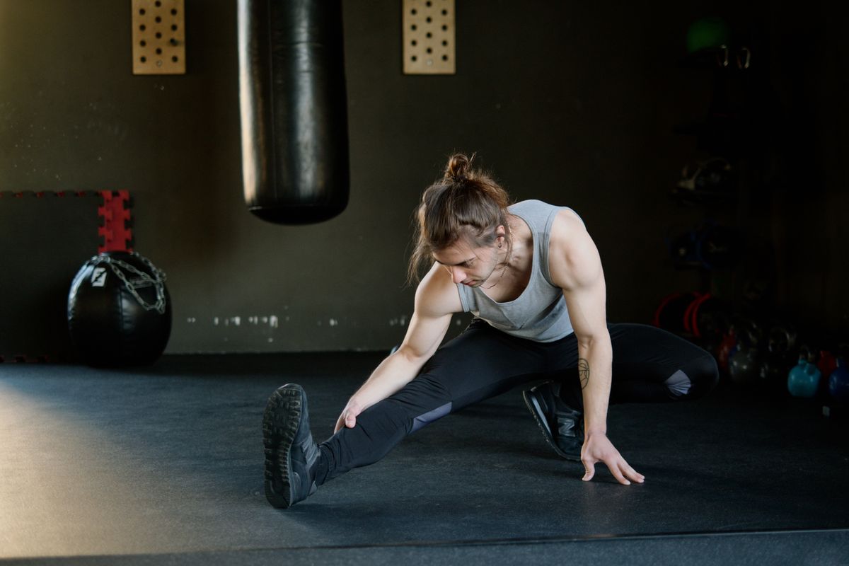 Weightlifting warm-up: a simple set-by-set example | the gym pro Man Stretching Beside Gym Equipment