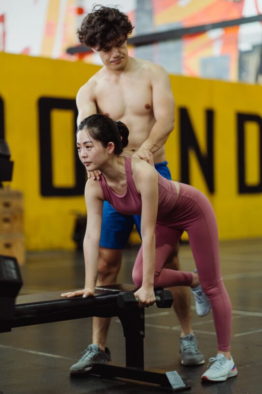 Gym etiquette: a practical guide for busy weight rooms | the gym pro Woman Practising A Deadlift With A Trainer Nearby